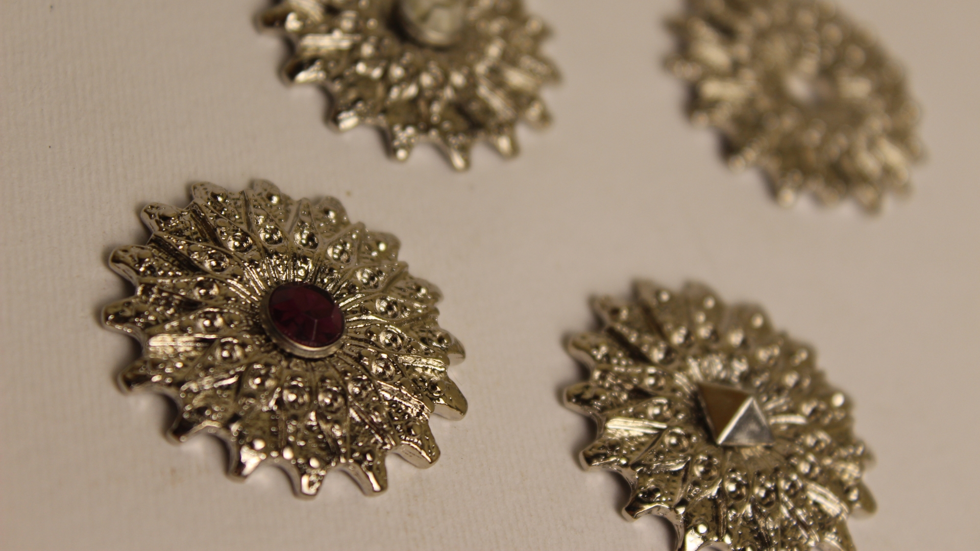 Decorative badge with an ornamental finish and a central stone